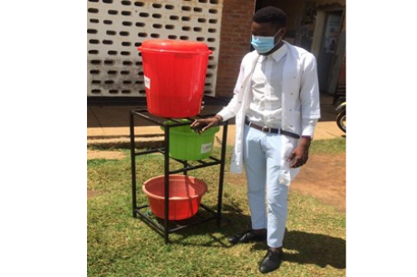 Health care worker stands by a hand washing station.