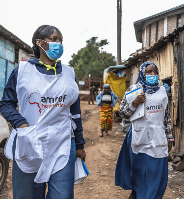 Two community health workers with masks and amref merchandise on